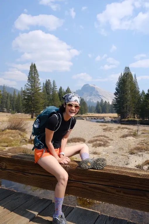 Milk sitting on a wooden bridge in Yosemite with Half Dome behind her